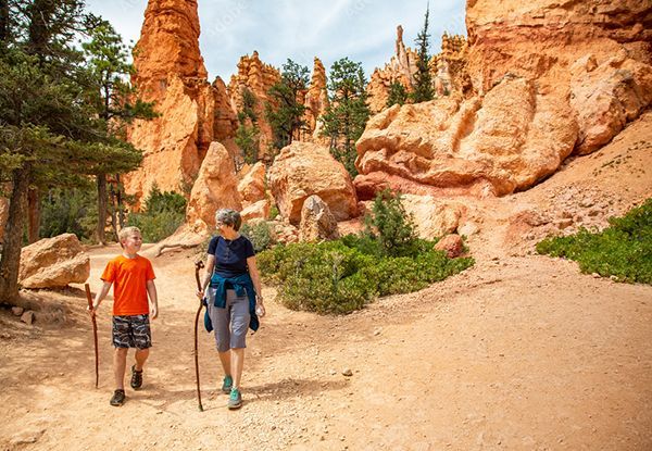 A woman and a boy are hiking in a canyon.