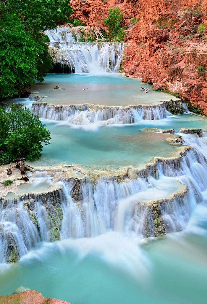 A waterfall in the middle of a river surrounded by trees and rocks.
