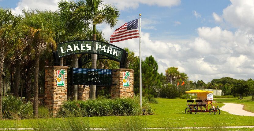 A sign for lakes park with an american flag in the background