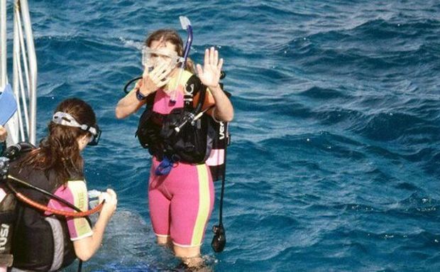 A woman in a wet suit is standing in the ocean.