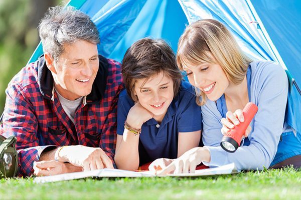 A family is laying in a tent reading a book.