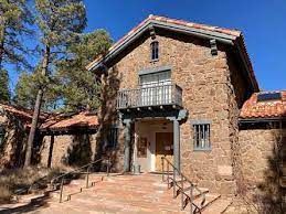 A large stone building with stairs leading up to it is surrounded by trees.