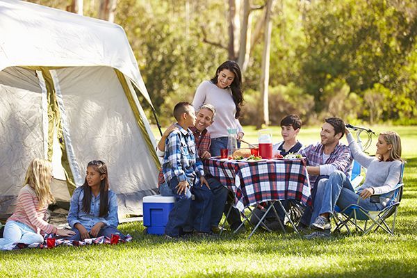 A group of people are having a picnic in front of a tent.