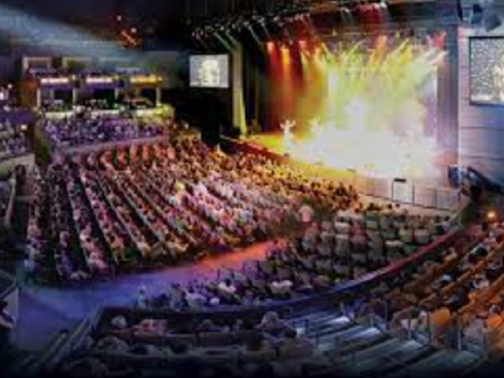 a large auditorium filled with people watching a concert .