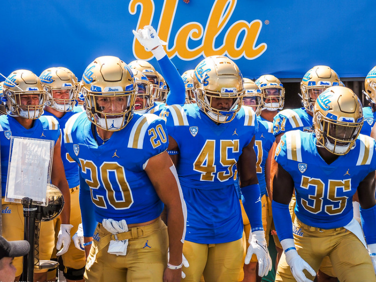 a group of ucla football players are walking out of the tunnel