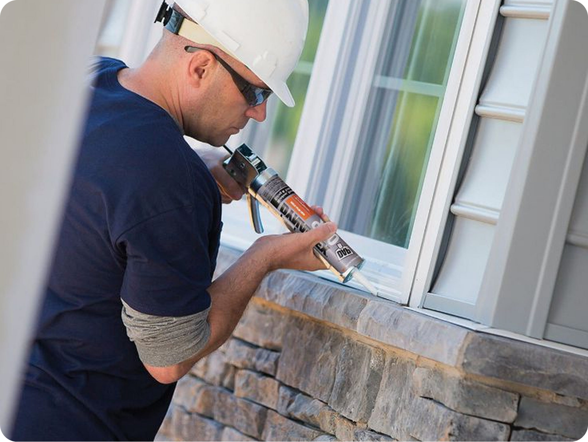 Worker applying sealant around a house window with a caulking gun