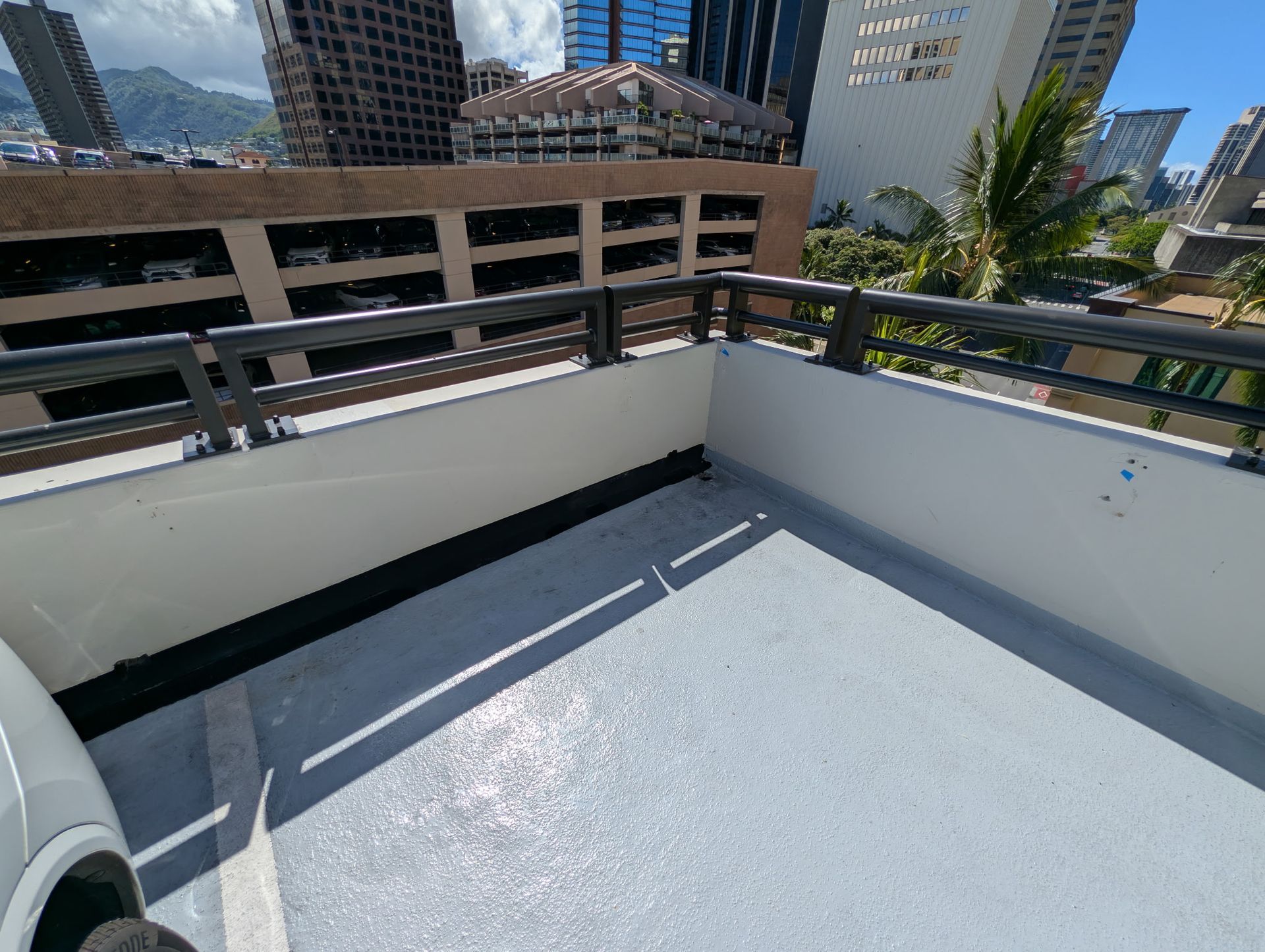 Sunny rooftop terrace with white walls, city buildings, and mountains in the background