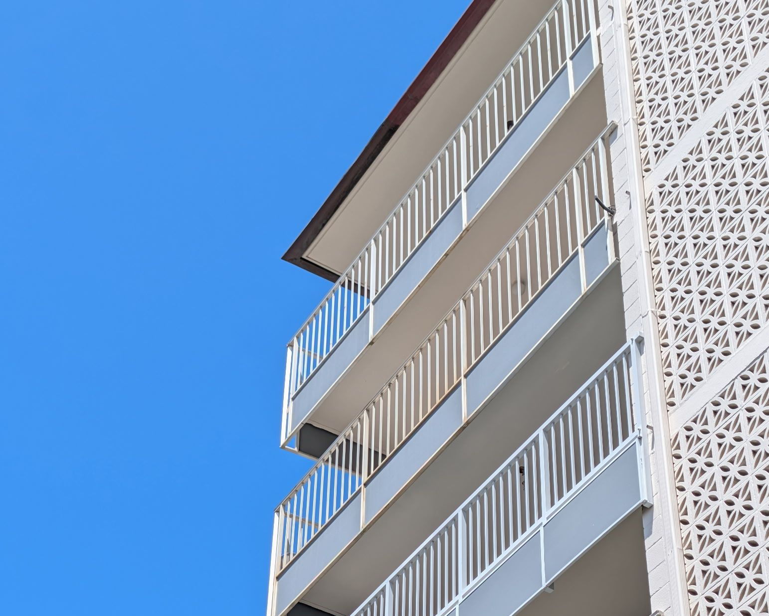 White apartment balconies against a bright blue sky