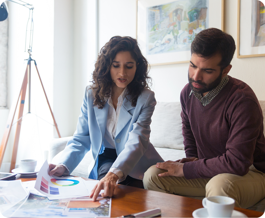 Two people reviewing charts and papers at a table in a bright office-like room