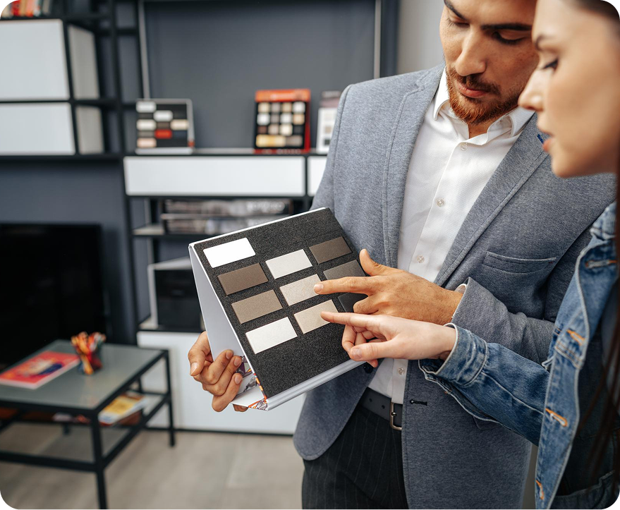 Two people review fabric or tile samples in a modern showroom, pointing at a sample board.