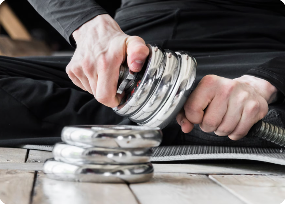 Hands squeezing a metal gripper on a wooden table, with stacked spring exercisers nearby