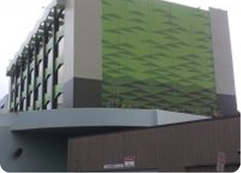 Modern building with green facade and gray exterior, viewed from a low angle.
