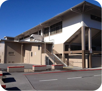 Modern building with outdoor stairs and a parking lot under a clear blue sky