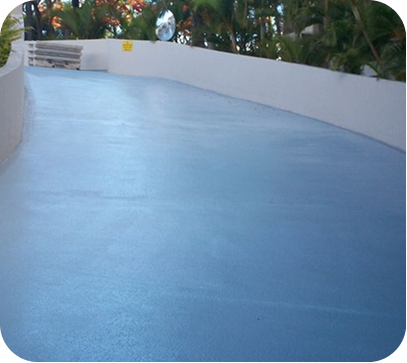 Blue curved walkway beside white walls and tropical plants