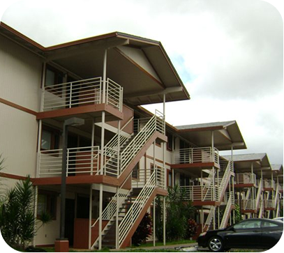 Apartment buildings with external staircases and balconies, seen from a parking lot