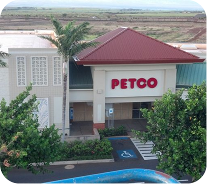 PETCO storefront with red roof, accessible parking space, and greenery outside.