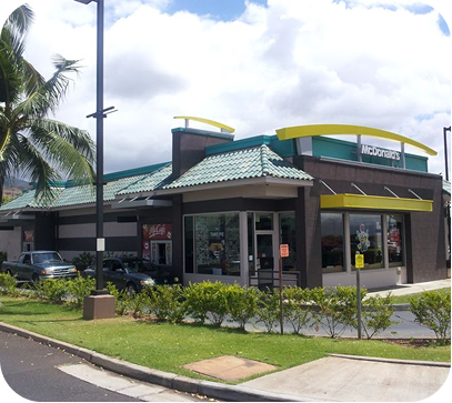 Fast-food restaurant with green roof and yellow trim on a sunny street corner