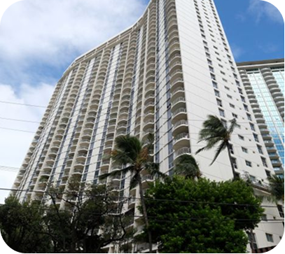 Tall white high-rise condo with curved balconies and palm trees against a blue sky