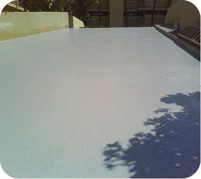 Flat white rooftop under sunlight with tree shadows and nearby buildings in the background