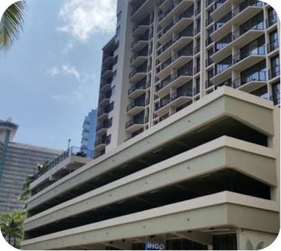 Modern high-rise building with stacked white balconies under a partly cloudy sky