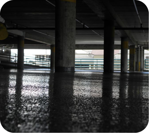Dim concrete parking garage with reflective wet floor and support pillars