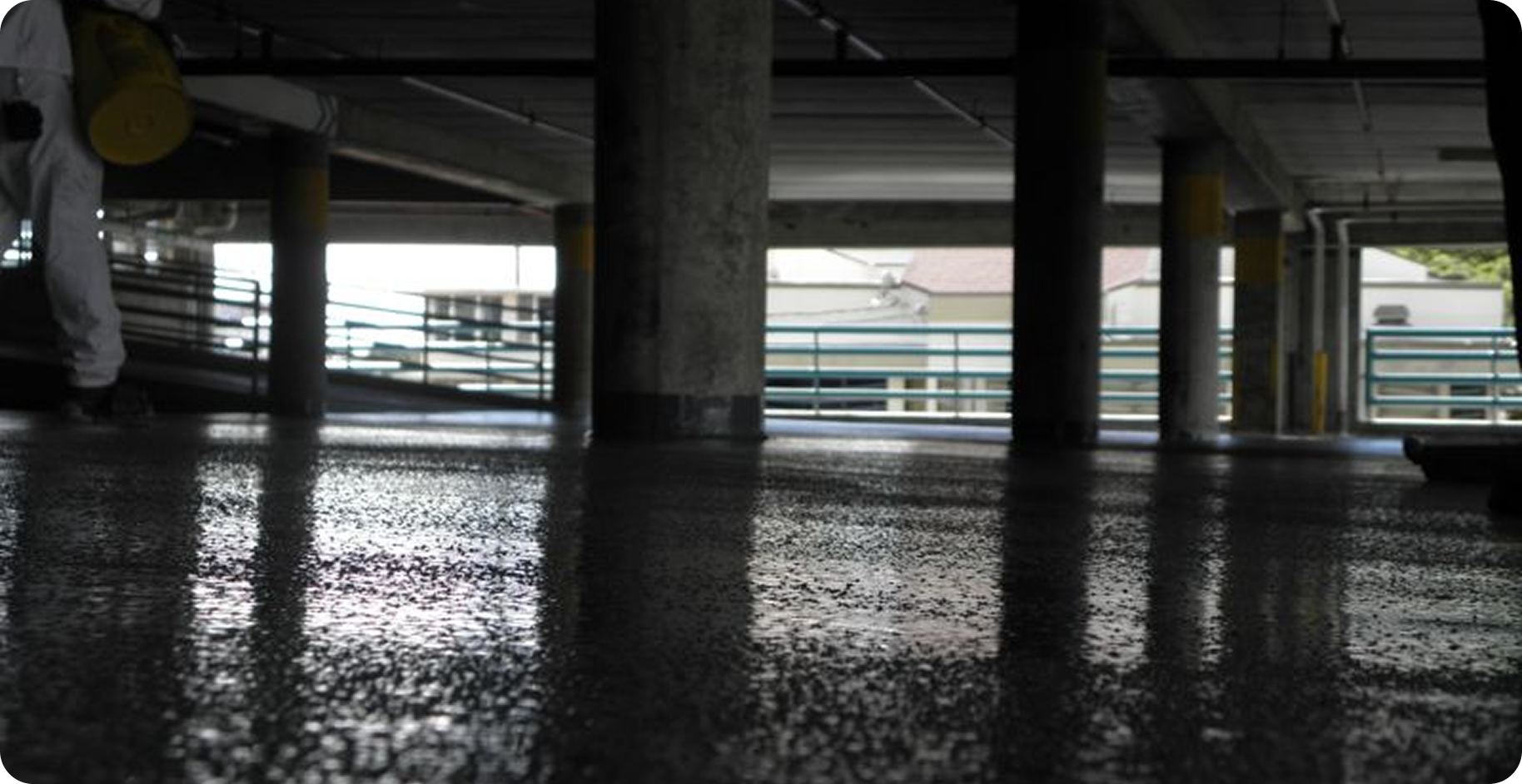 Empty parking garage with wet reflective floor and concrete pillars