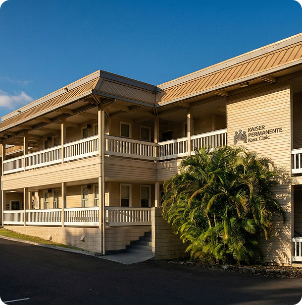 Two-story tan building with wraparound balcony and palm trees under a clear blue sky