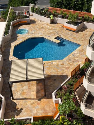 Luxury resort pool with lounge chairs, palm trees, and ocean view under umbrellas