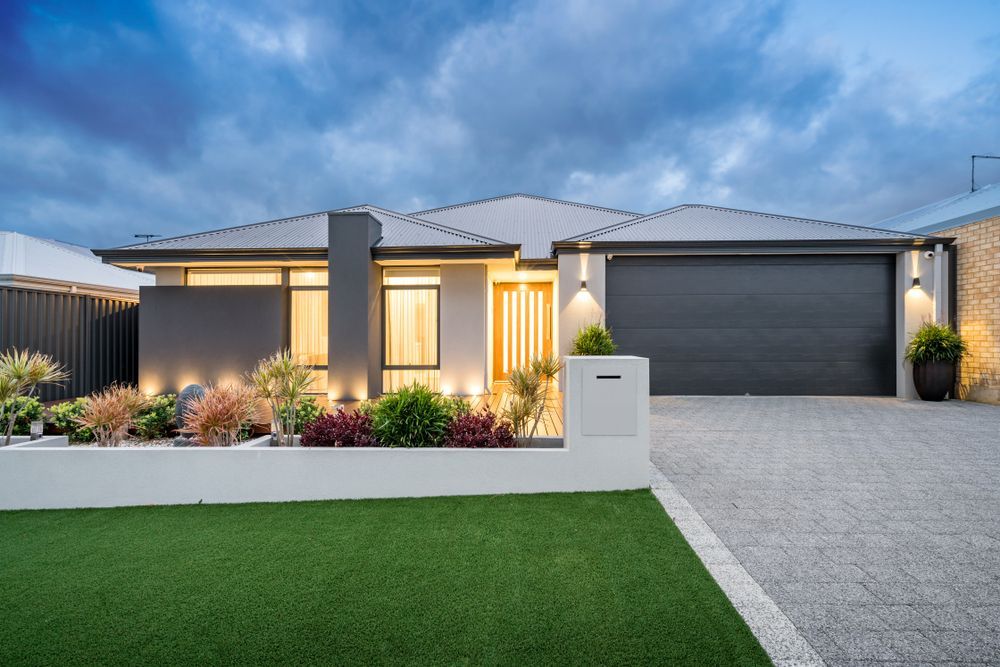 Modern single-story house with a landscaped front yard, green lawn, and double garage at dusk - Harris Design & Building Concepts In Jubilee Pocket, QLD