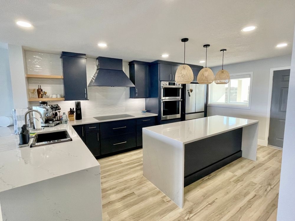 Modern kitchen with navy cabinets, white counters, large island, and pendant lights Harris Design & Building Concepts In Jubilee Pocket, QLD