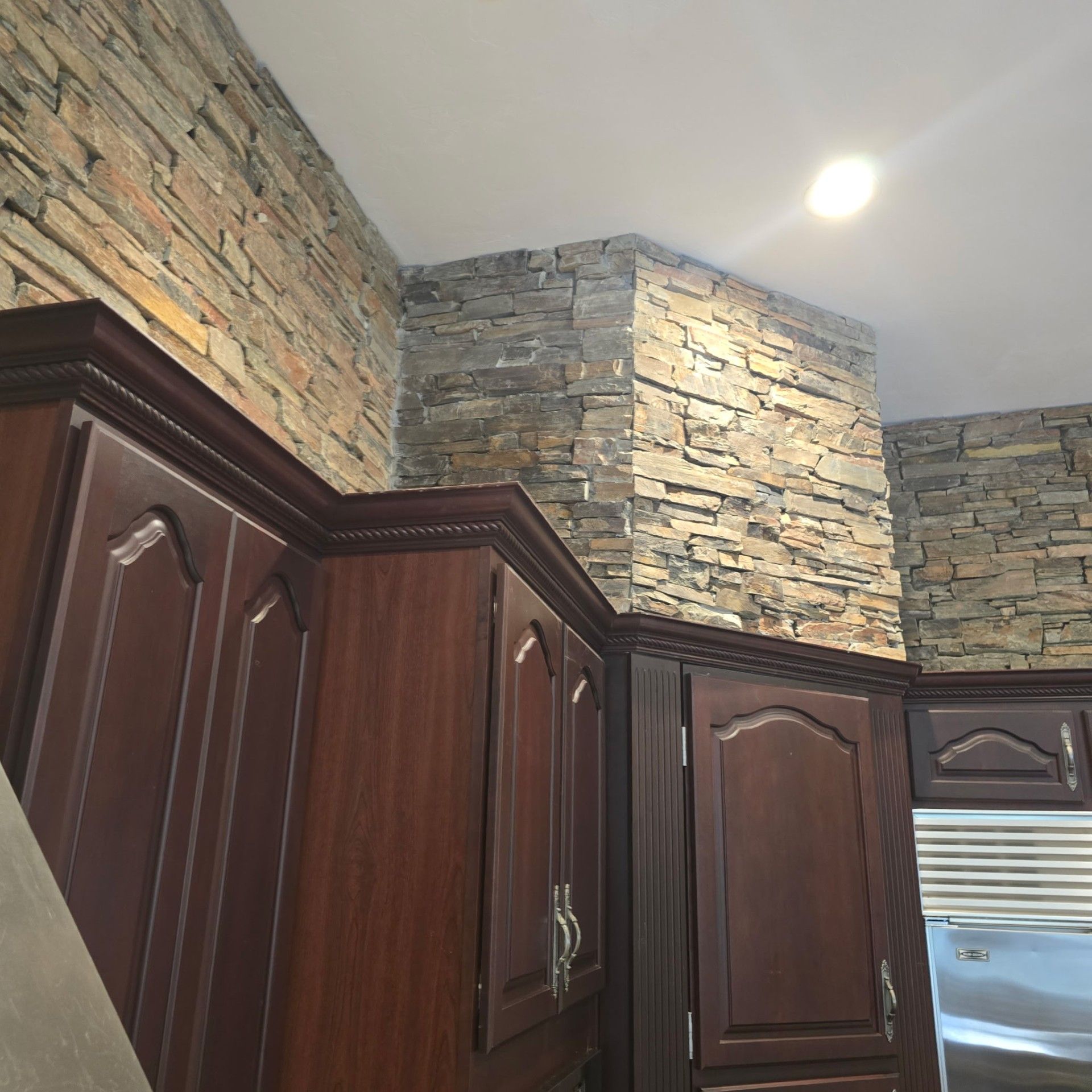 Kitchen with dark wood cabinets and stacked stone walls extending to the ceiling