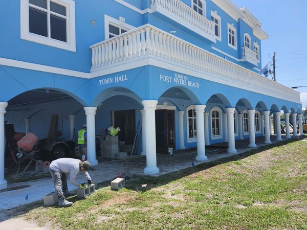 Workers building in front of a bright blue building with white columns and trim.