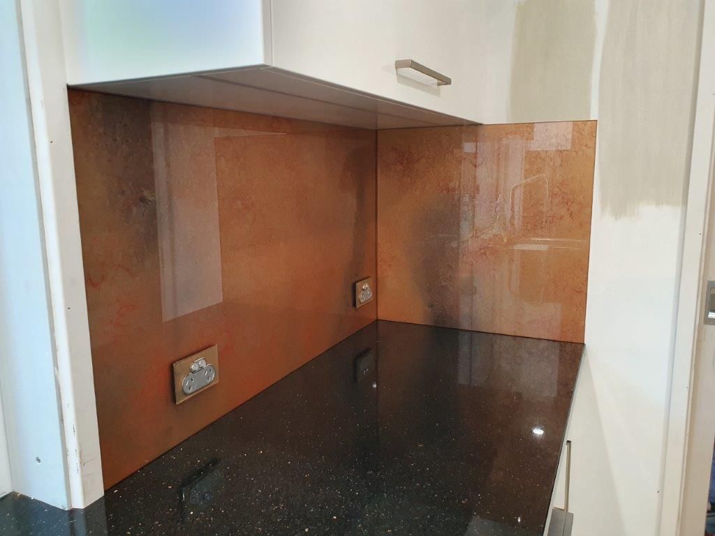 A kitchen with a copper backsplash and a black counter top.