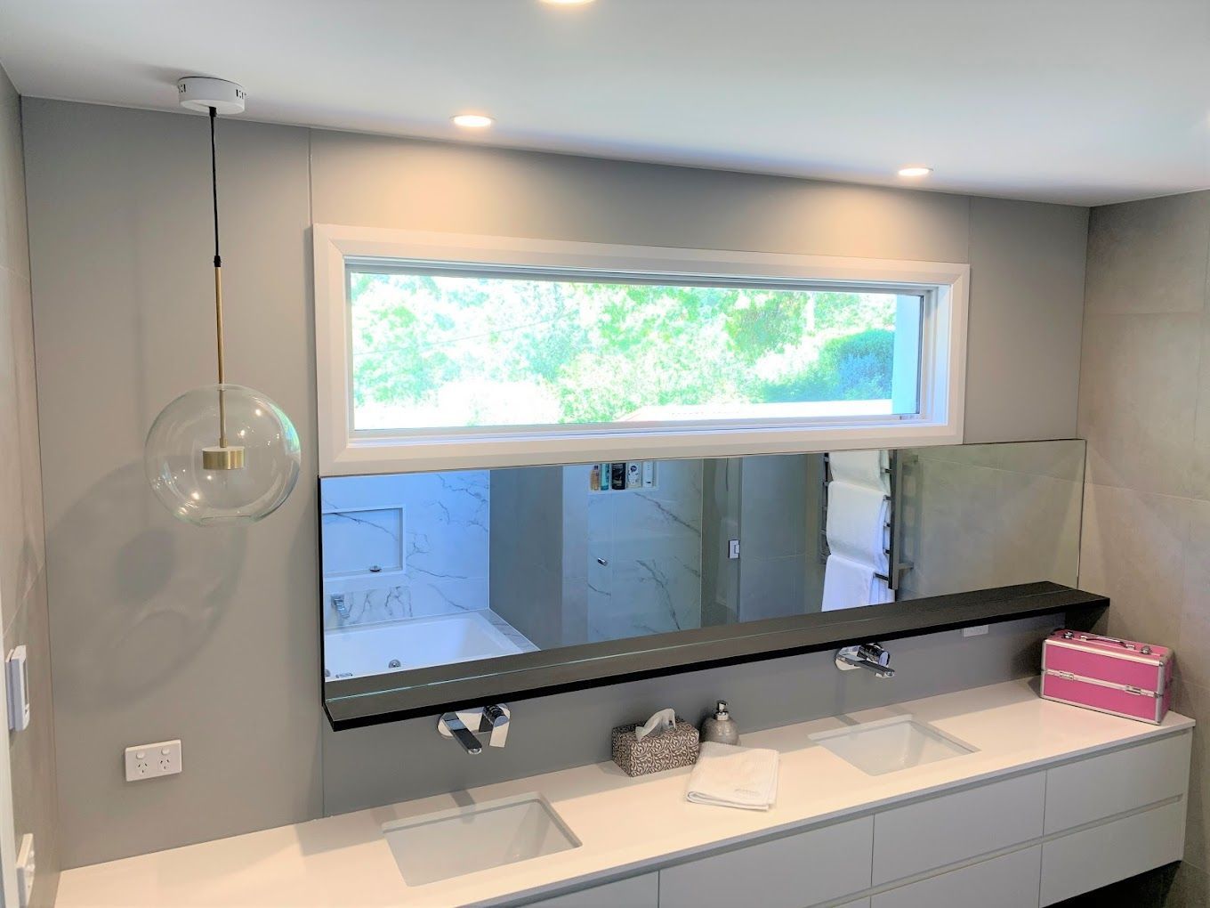 A bathroom with two sinks , a large mirror and a window.