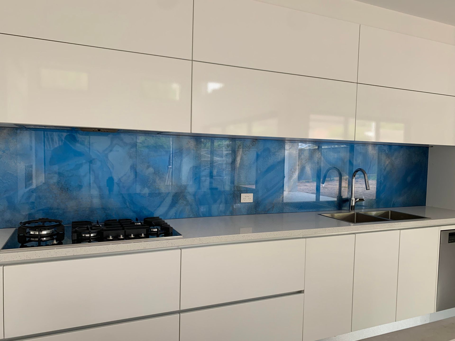 A kitchen with white cabinets and a blue backsplash.