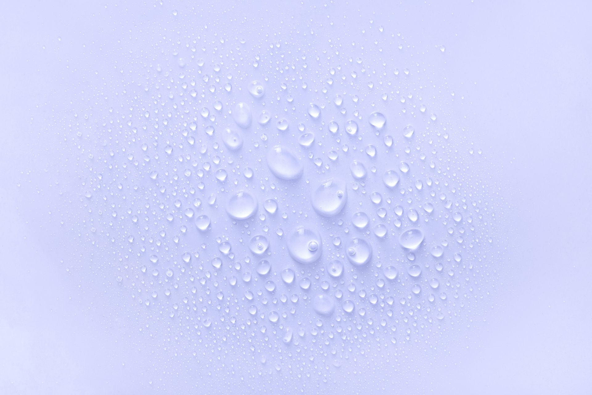 Wassertropfen auf einer violetten Oberfläche auf violettem Hintergrund.
