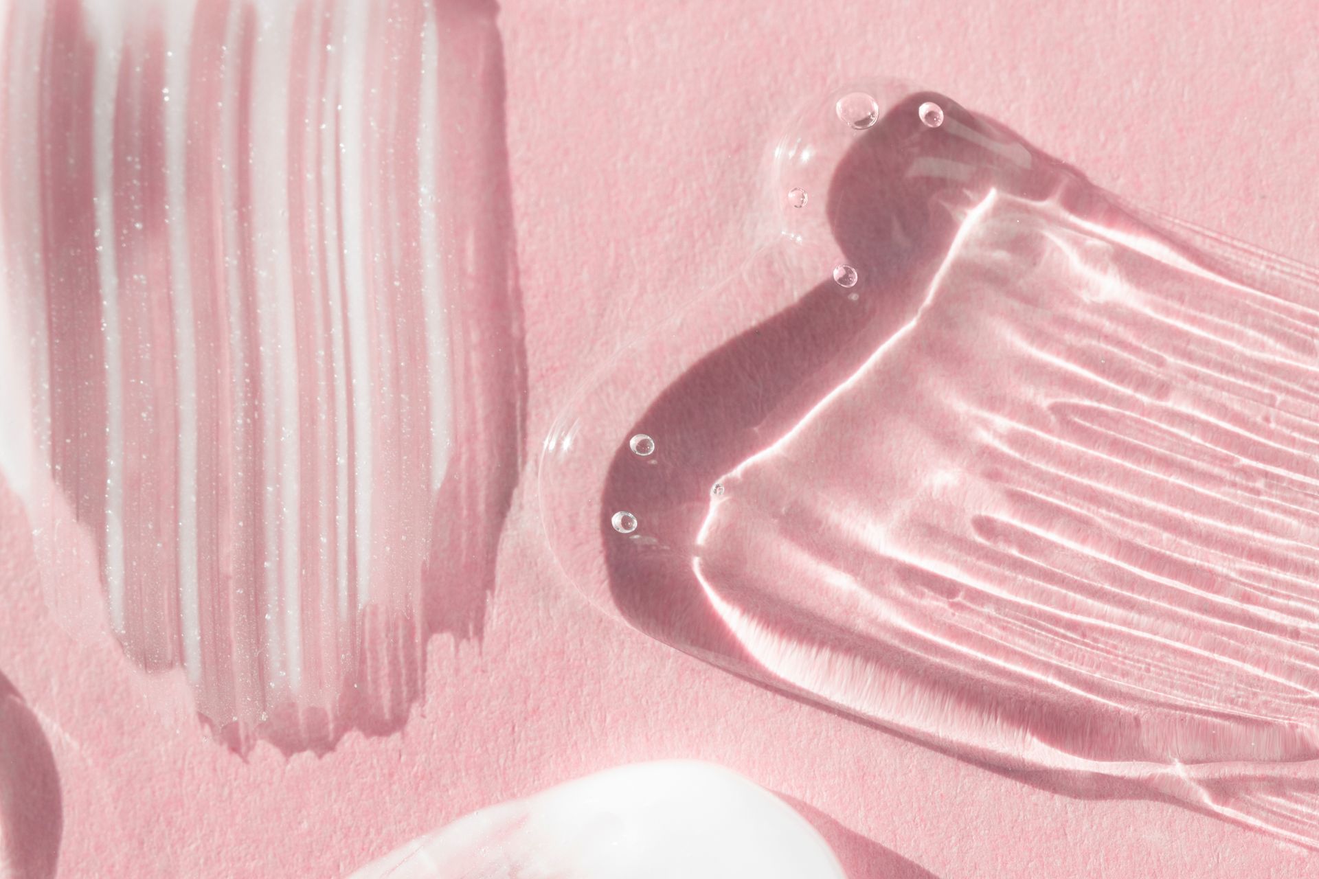 Eine Nahaufnahme eines Pinselstrichs Flüssigkeit auf einer rosa Oberfläche.