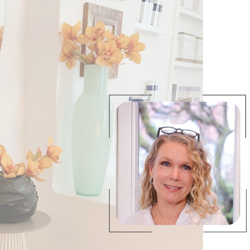 Eine Frau mit Brille lächelt vor einer Vase mit Blumen.