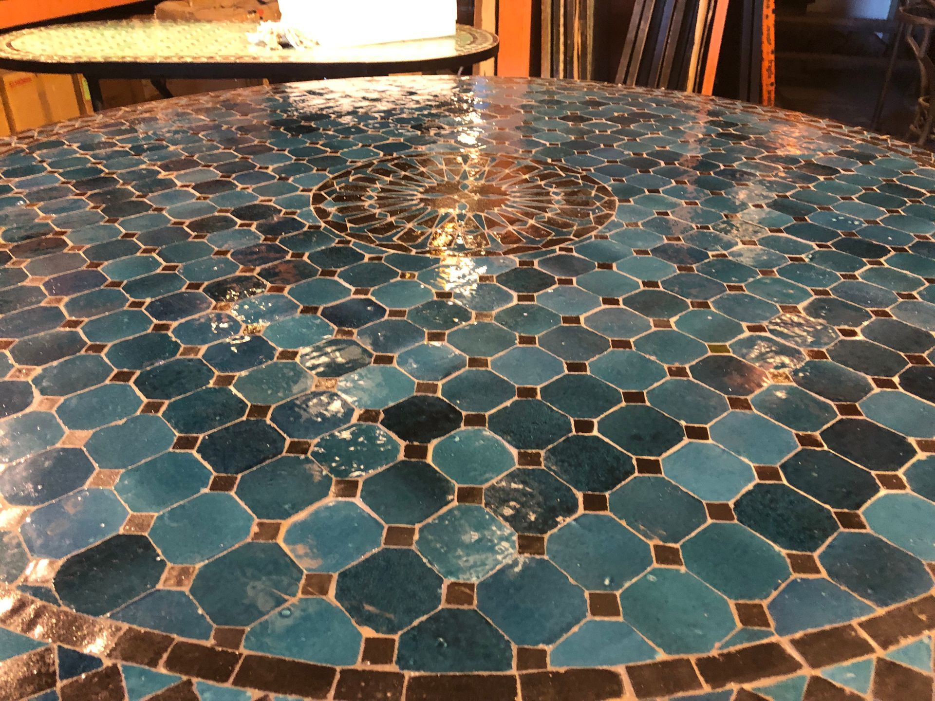Ronde handgemaakte tafel met een blad van mozaïektegels  uit Marokko in blauwe en zwarte tinten.