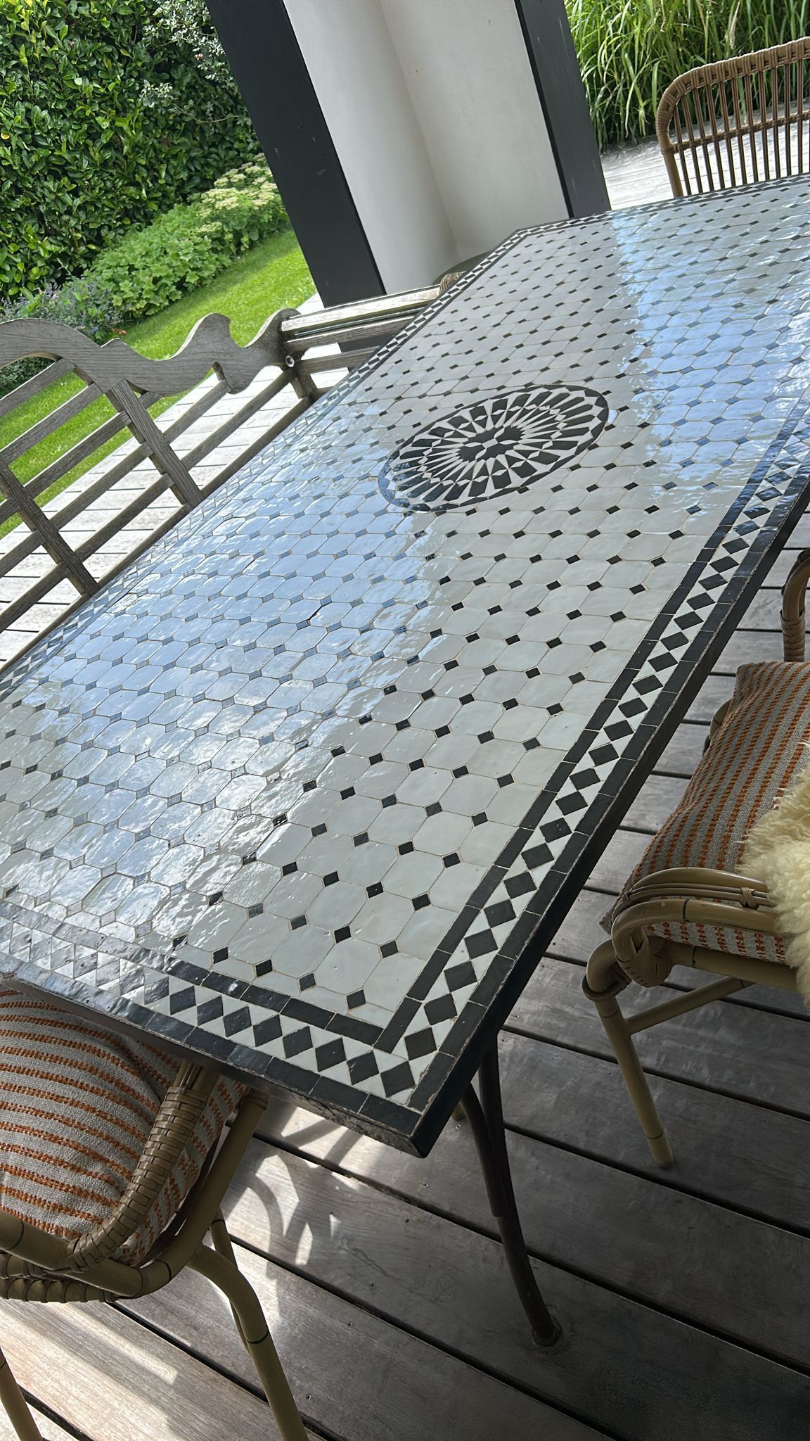 Marokkaanse Mozaiek eettafel voor buiten met mozaïektegelblad, omringd door stoelen op een houten terras.