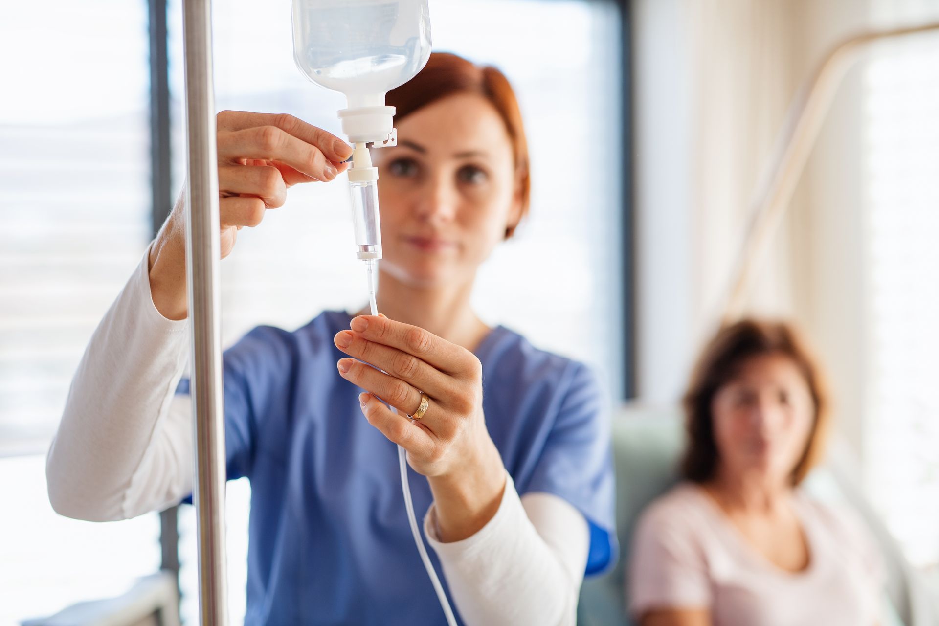 A nurse is preparing an IV drip for a patient in a room.