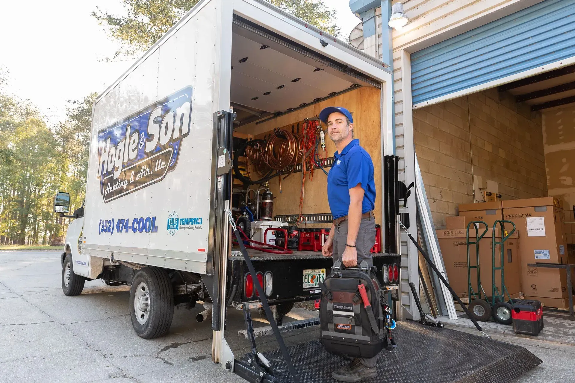 HVAC technician exiting a work truck. The truck is open, showing tools and supplies.
