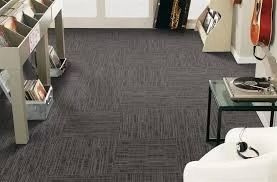 Dark gray patterned carpeted floor in a room, with record storage, stereo equipment, and a white chair.