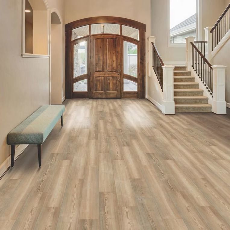Spacious entryway with light wood-look floors, a bench, wooden door, and staircase.