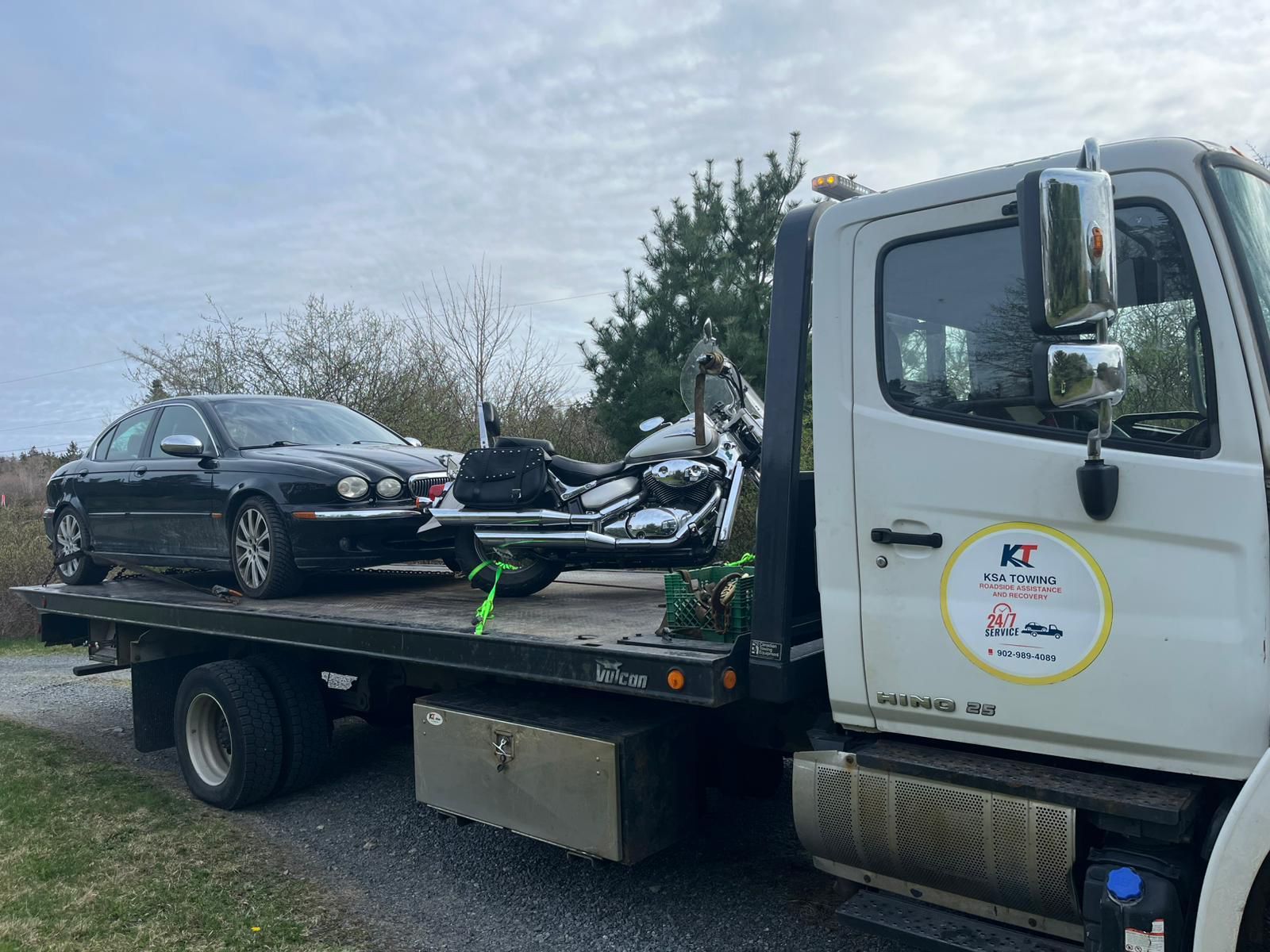 Tow truck carrying a black sedan and a damaged scooter on a flatbed