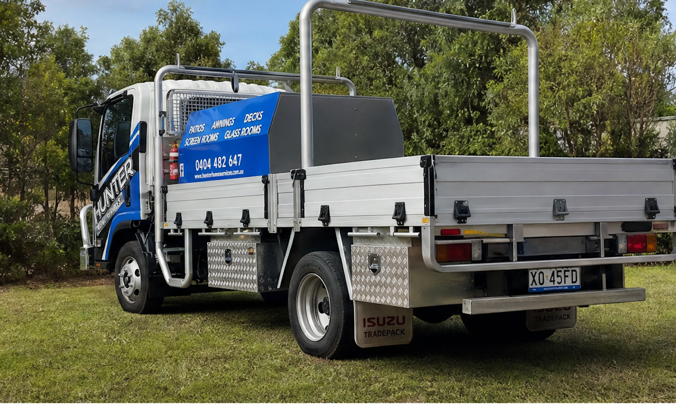 Blue and white flatbed truck parked on grass with trees in the background