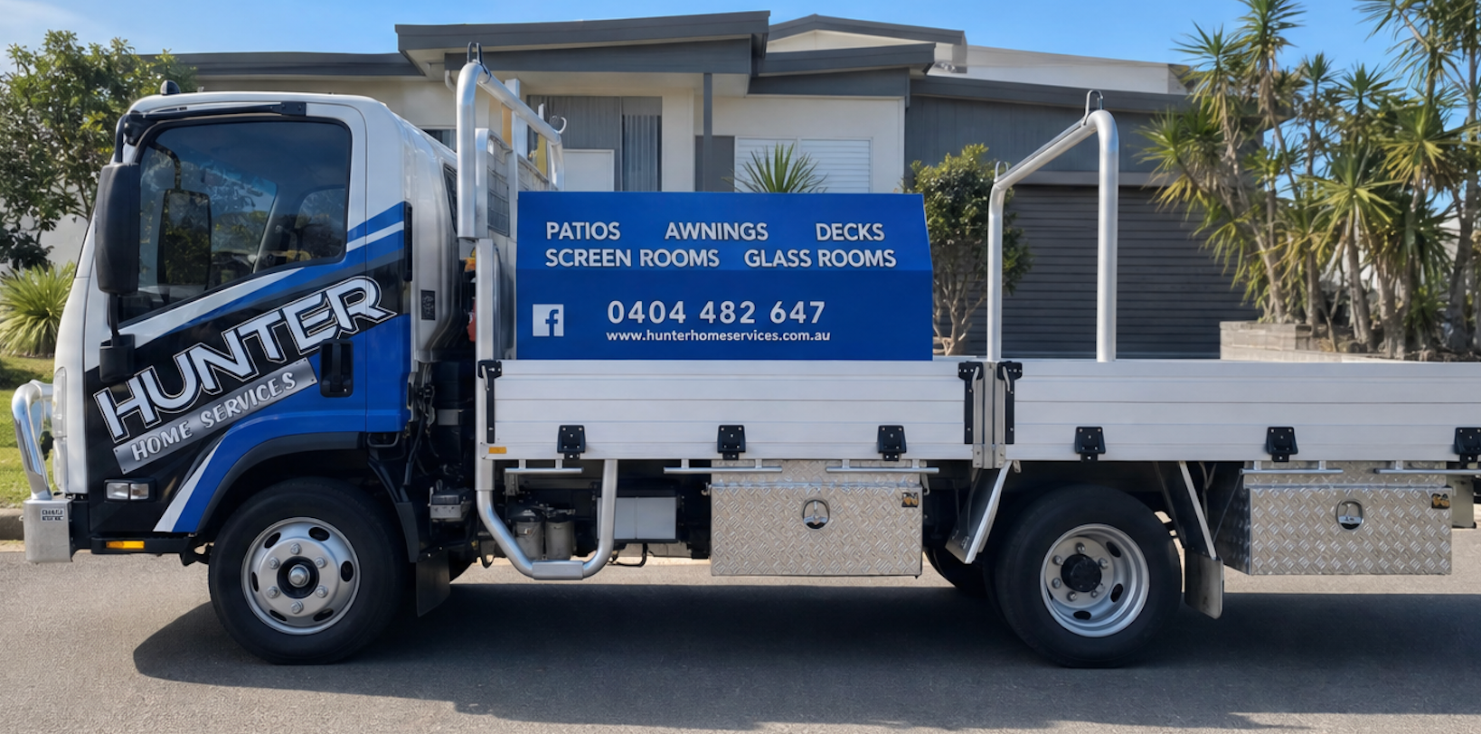 Blue-and-white work truck parked outside a house, with service signage on the side.