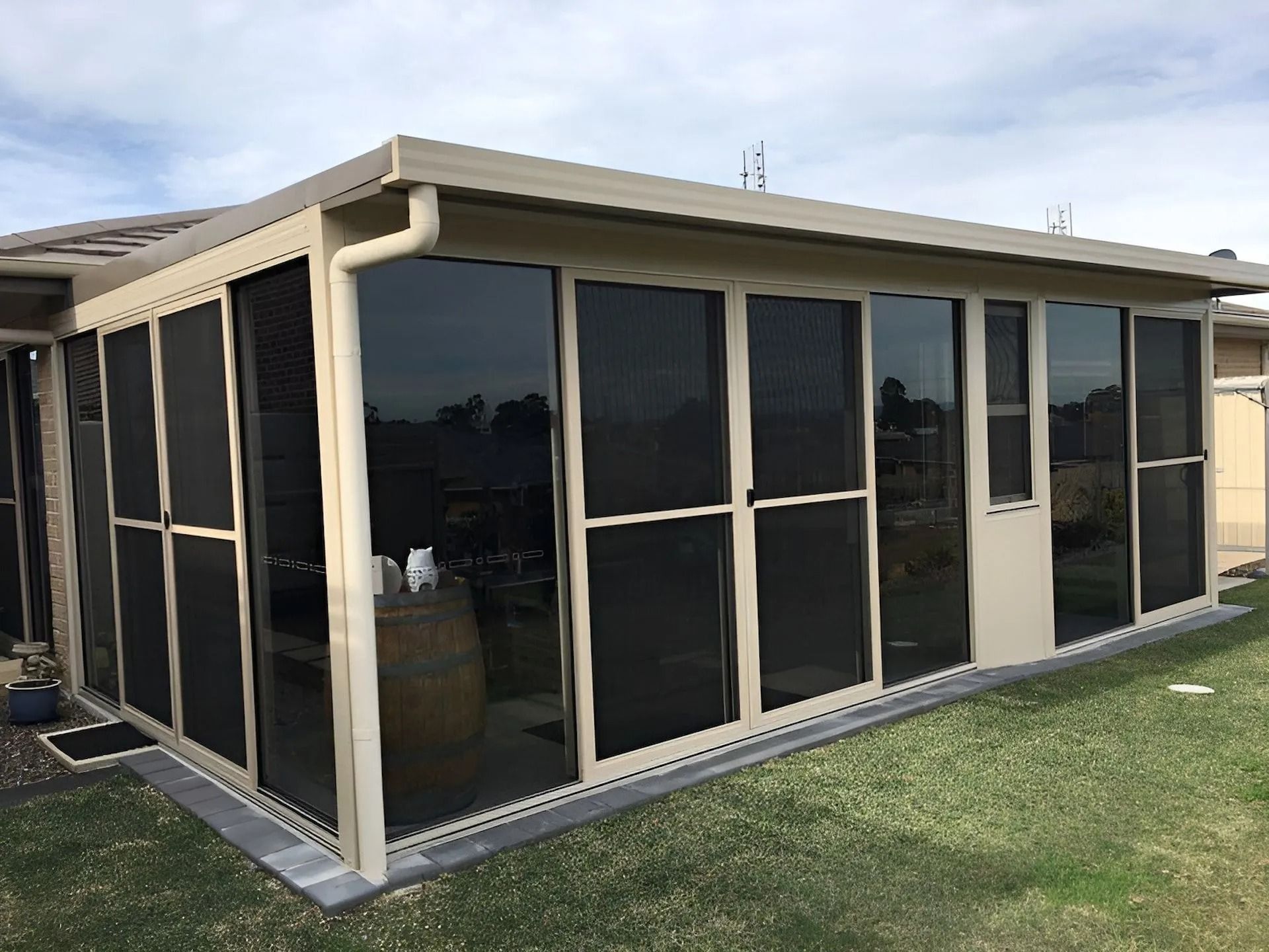 Screened porch with black mesh panels and tan trim on a grassy yard