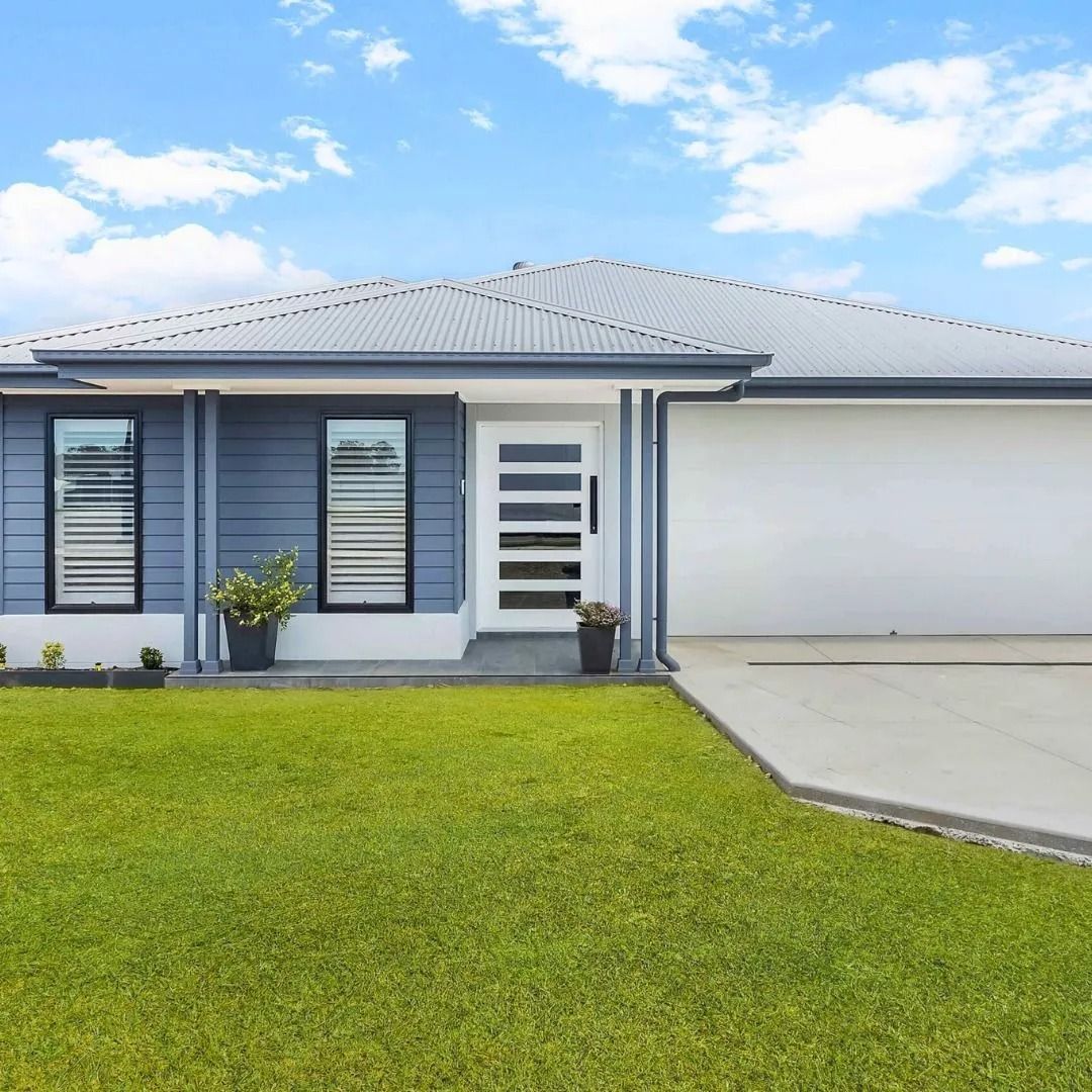 Modern single-story gray house with white garage, front lawn, and blue sky