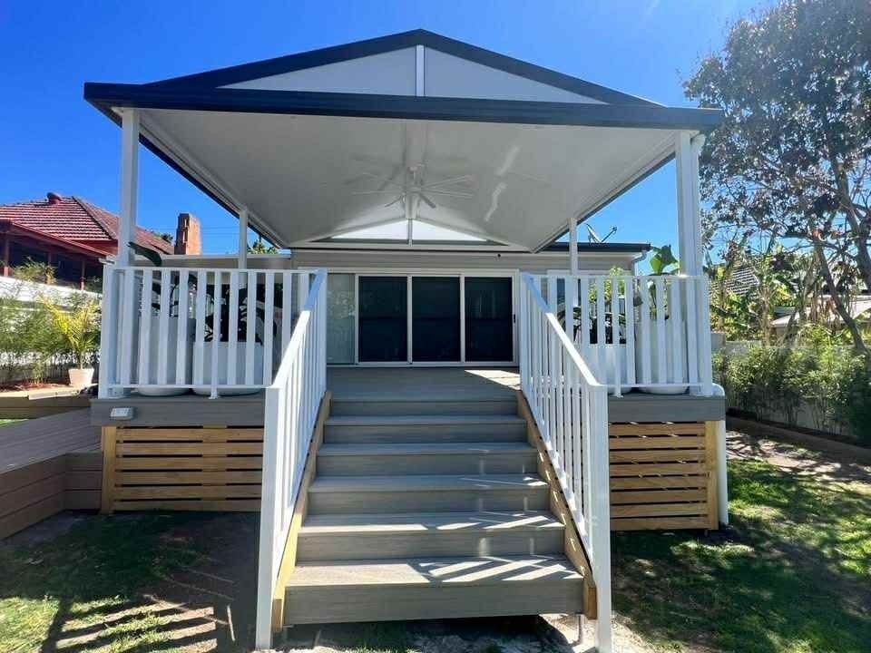 White-railed backyard deck with central steps leading to a shaded gazebo-style canopy